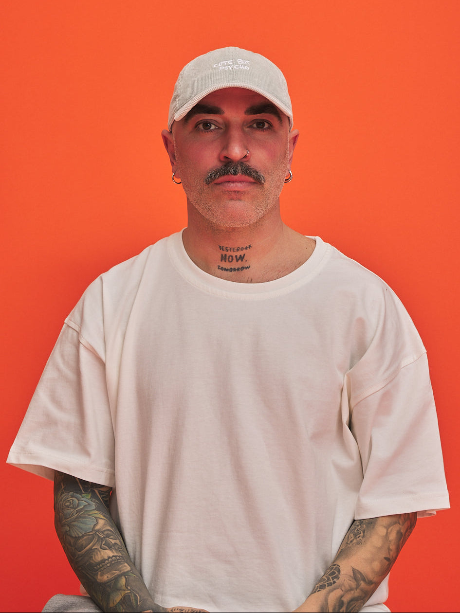 Man wearing a white cap and t-shirt against an orange background
