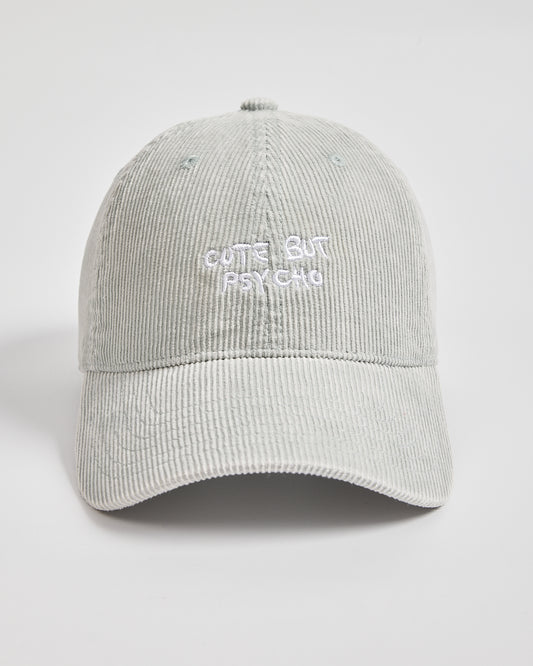 Light grey corduroy cap with 'Cute But Psycho' text on a light grey background