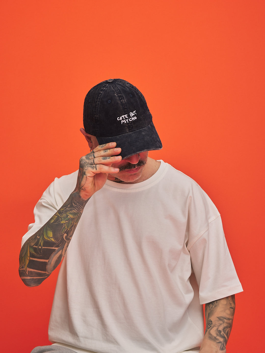 Person wearing a navy blue corduroy cap with text on an orange background