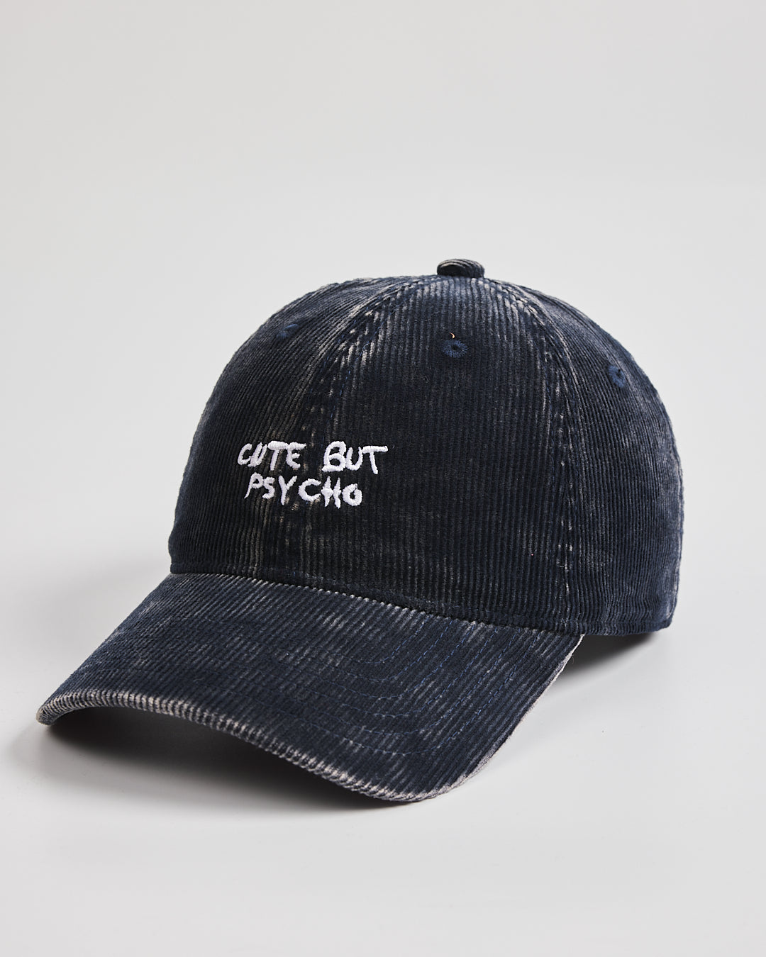 Navy blue corduroy cap with 'Cute But Psycho' text on a gray background