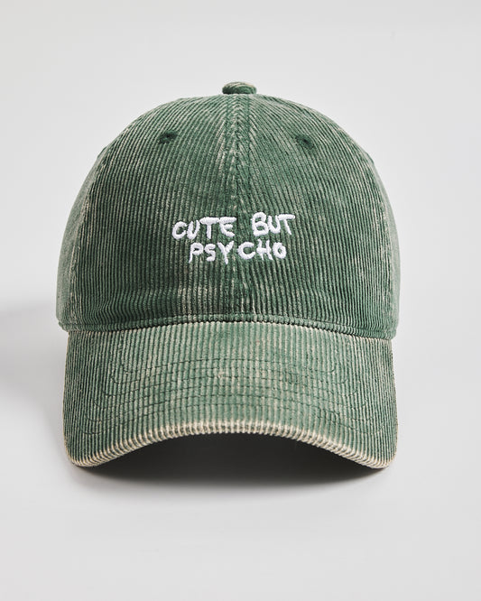 Green corduroy cap with 'Cute But Psycho' text on a light gray background