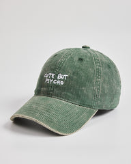 Green corduroy cap with 'Cute But Psycho' text on a light gray background