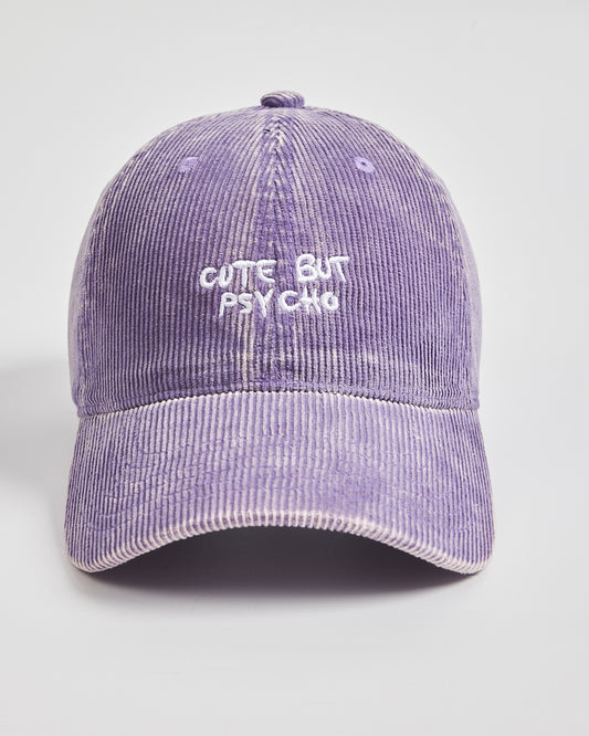 Purple corduroy cap with 'Cute But Psycho' text on a light gray background