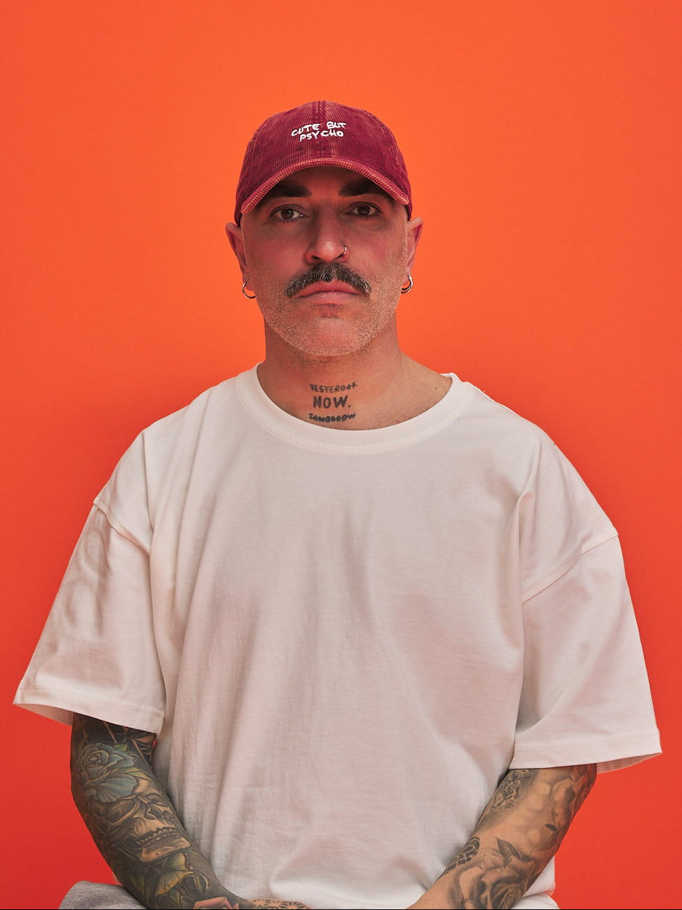 Man wearing a red cap and white t-shirt against an orange background