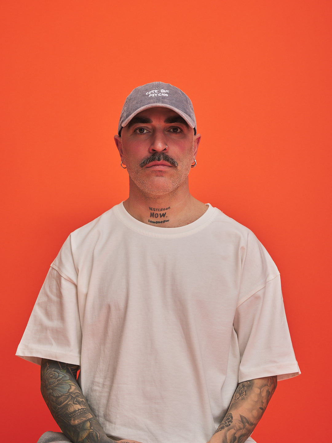 Man wearing a gray cap and white t-shirt against an orange background