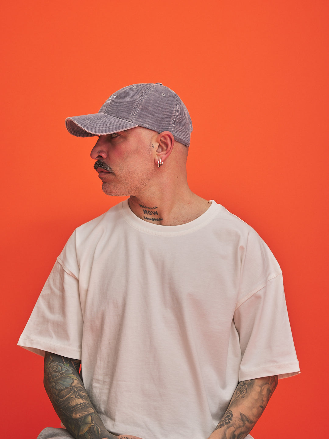 Man wearing a gray cap and white t-shirt against an orange background