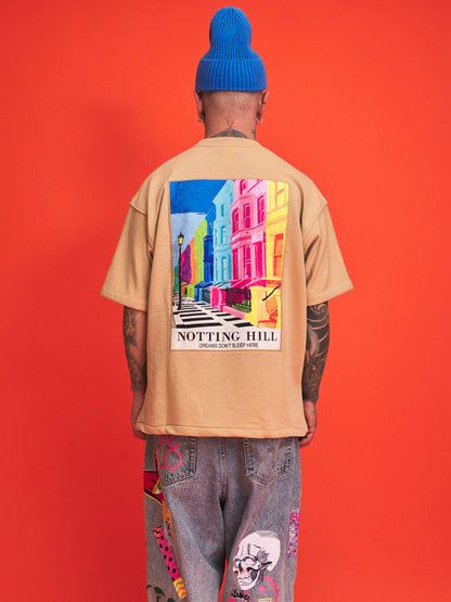 Person wearing a beige shirt with a colorful 'Notting Hill' design on the back against an orange background