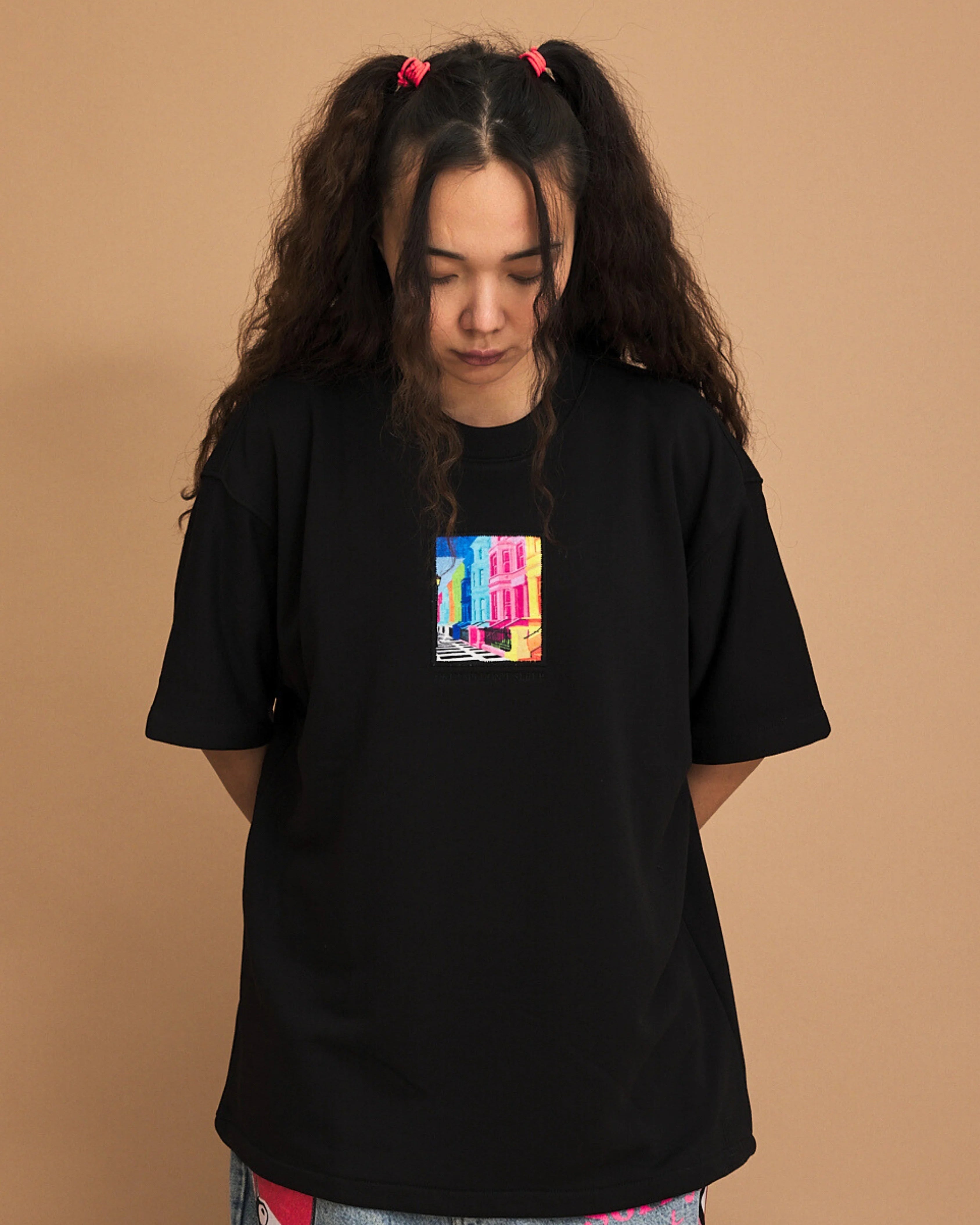 Person wearing a black t-shirt with a colorful graphic on a brown background