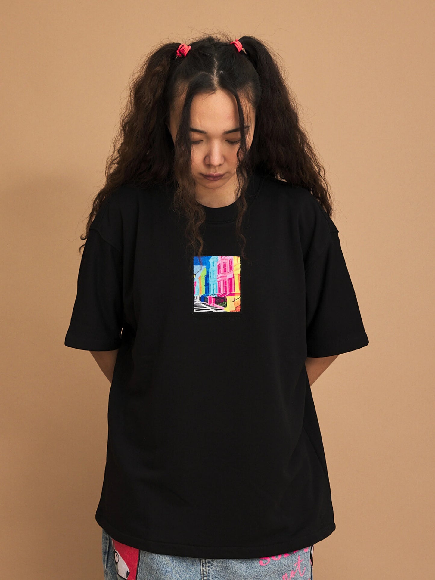 Person wearing a black t-shirt with a colorful graphic on a brown background