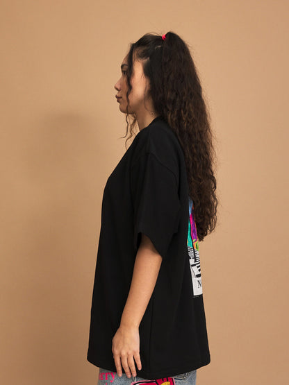 Person wearing a black t-shirt with colorful designs on a brown background