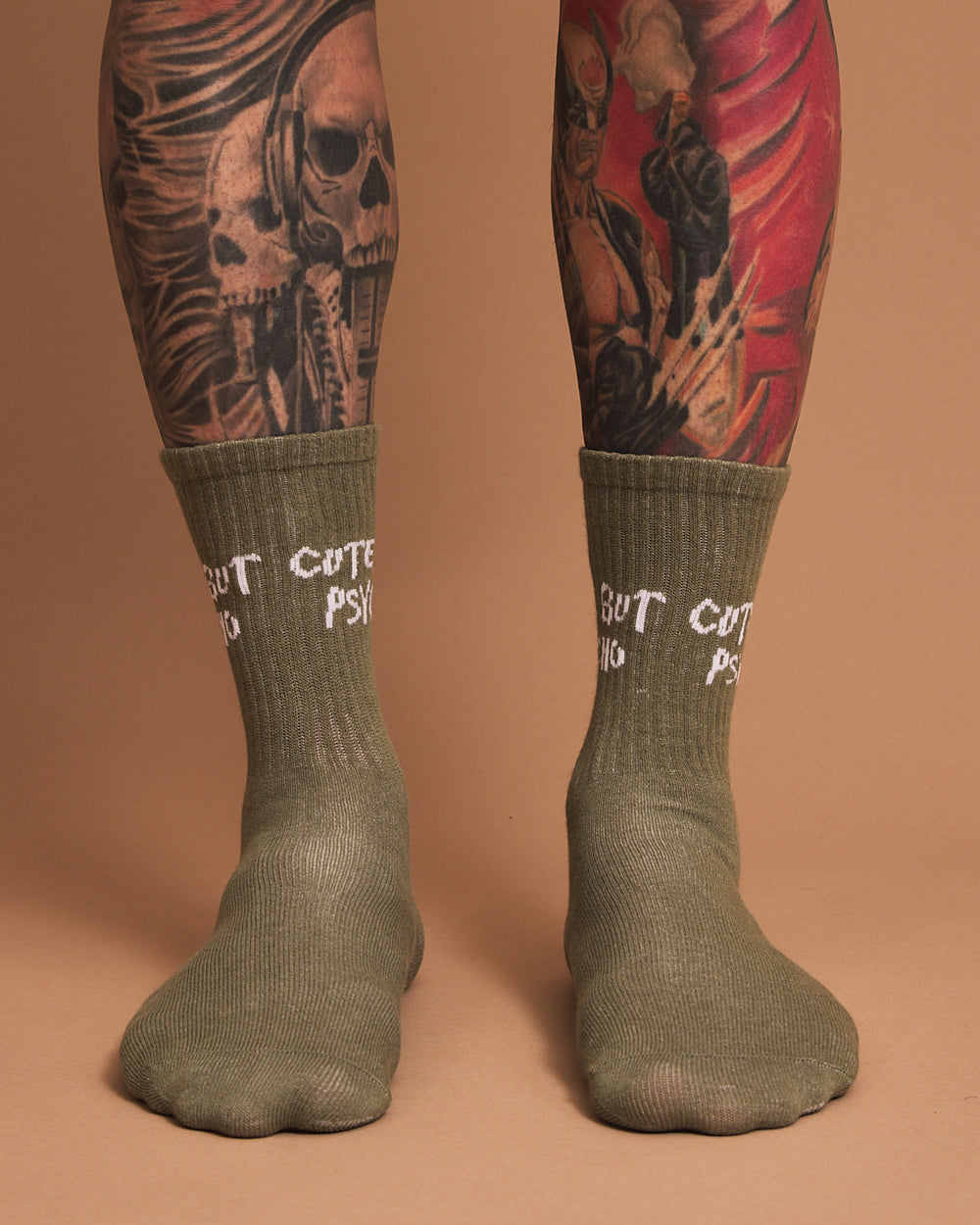 Green socks with text worn by a person with tattoos on a brown background