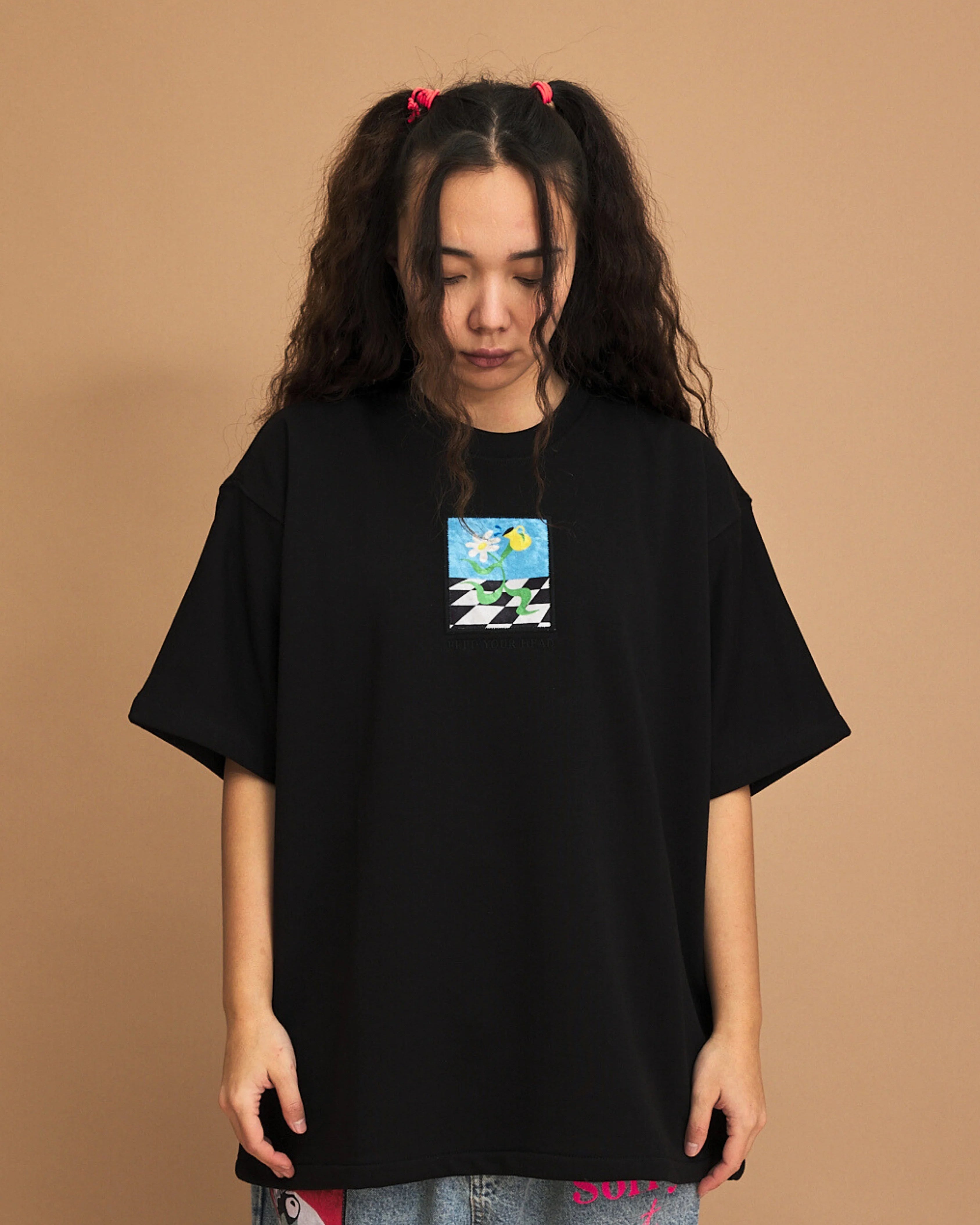 Person wearing a black t-shirt with a small graphic on a brown background