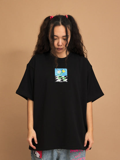 Person wearing a black t-shirt with a small graphic on a brown background