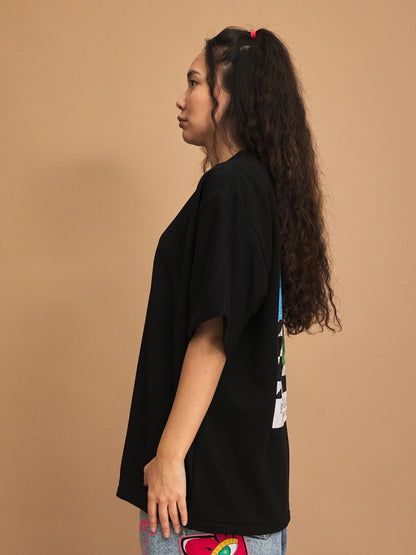 Person wearing a black t-shirt with colorful designs on a brown background