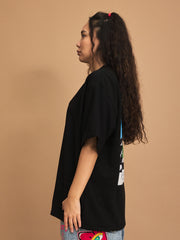 Person wearing a black t-shirt with colorful designs on a brown background