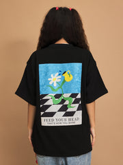Person wearing a black t-shirt with a colorful graphic and text on the back against a brown background