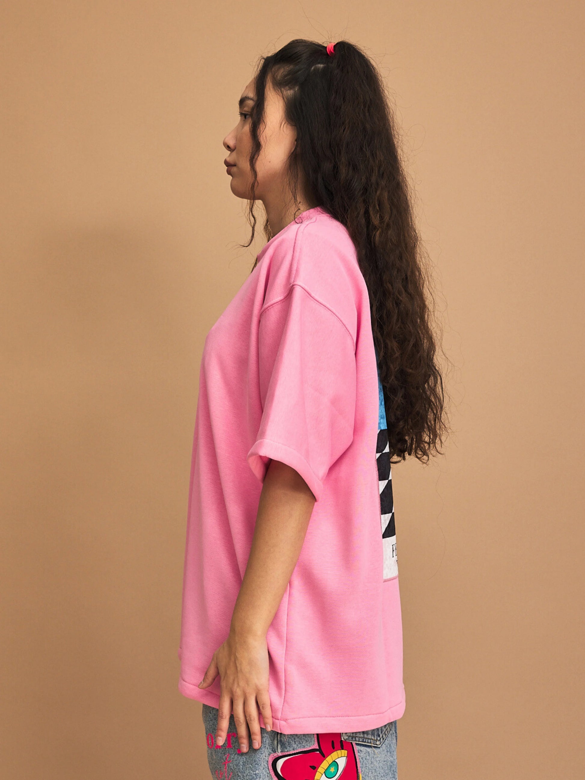 Person wearing a pink t-shirt with colorful designs on a brown background
