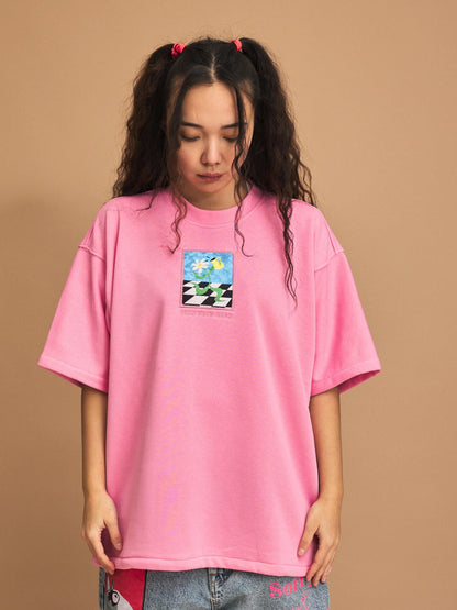 Person wearing a pink t-shirt with a graphic design on a brown background