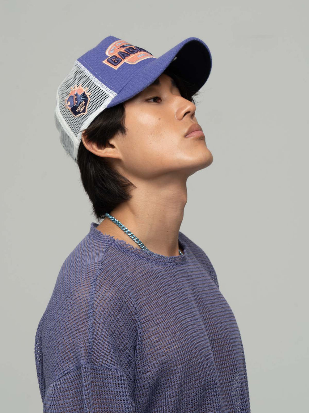 Person wearing Gagarin Purple Trucker Hat on a gray background