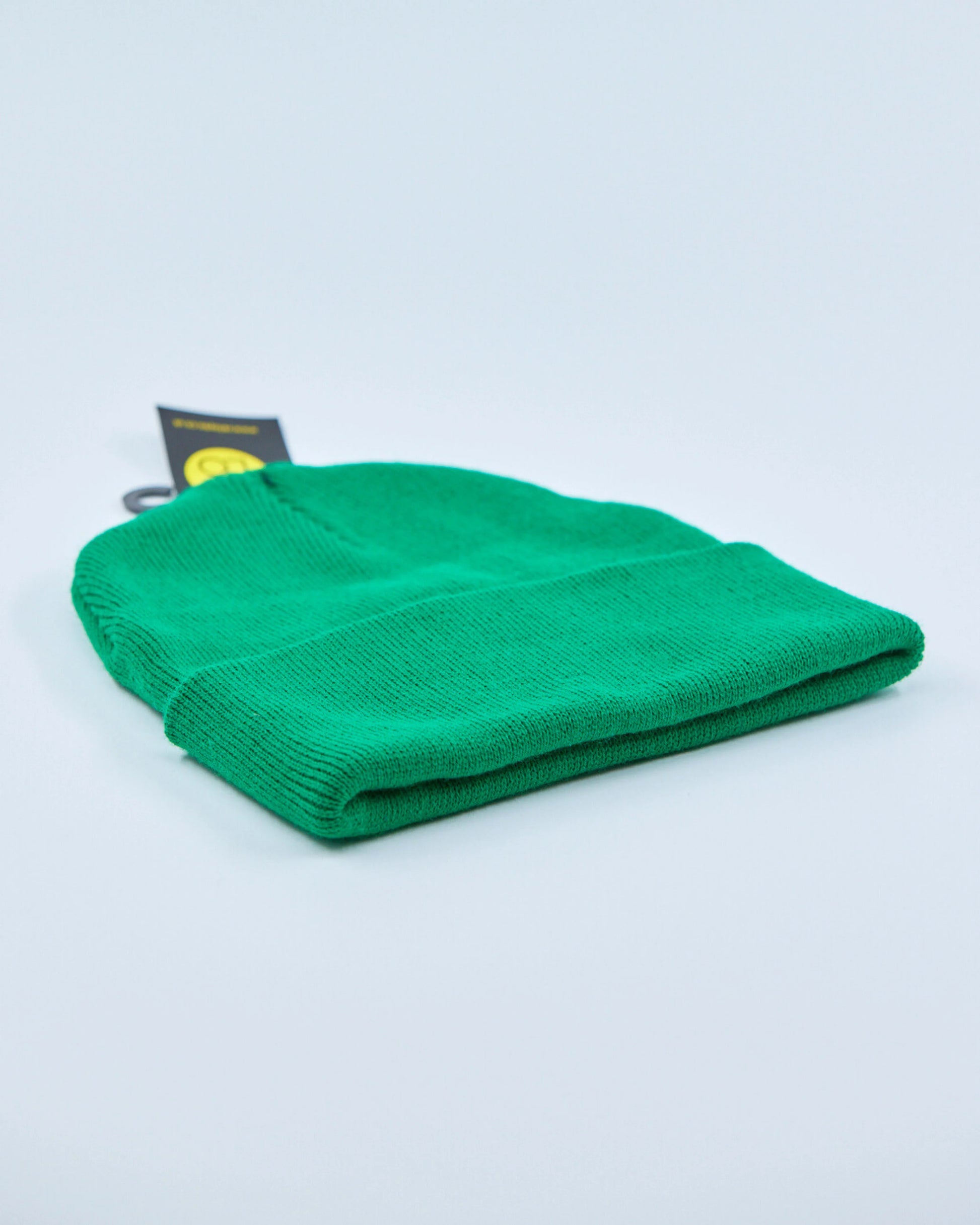 Green beanie with a tag on a light gray background