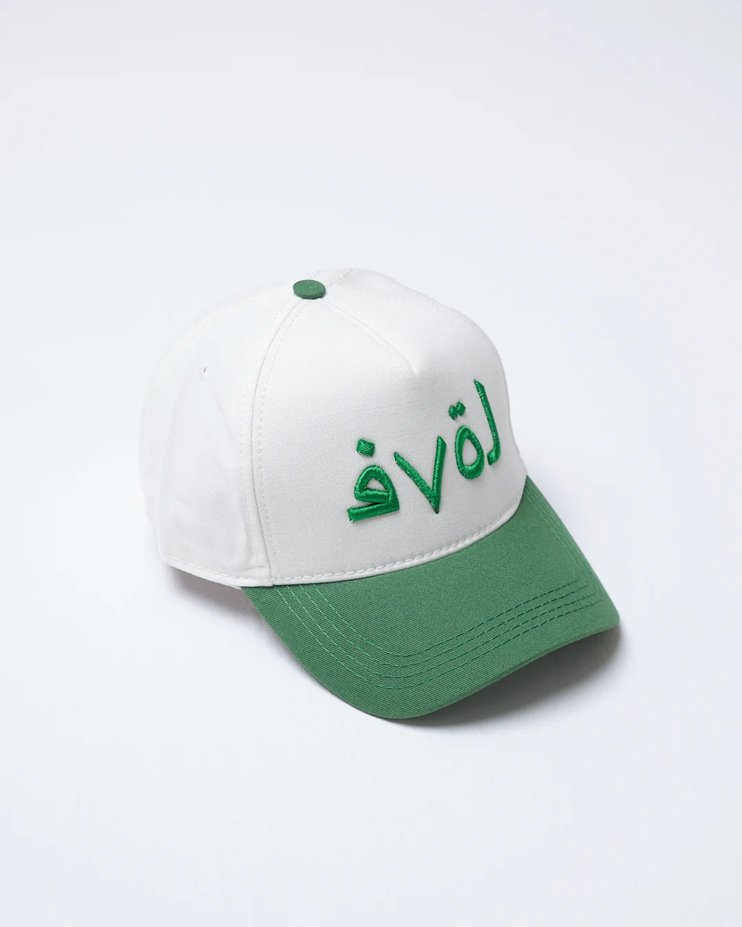 White cap with green brim and embroidered text on a white background