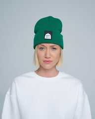 A person wearing green beanie with a duck patch on a gray background