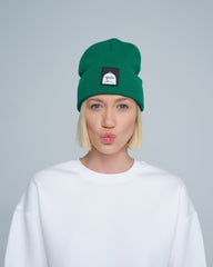 A person wearing green beanie with a duck patch on a gray background