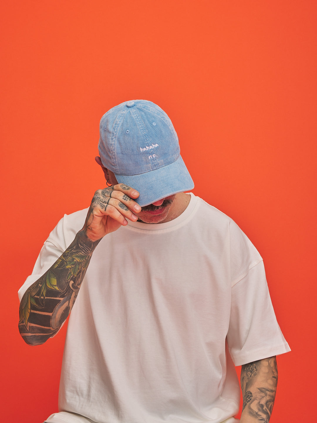 Person wearing a blue cap and white t-shirt against an orange background