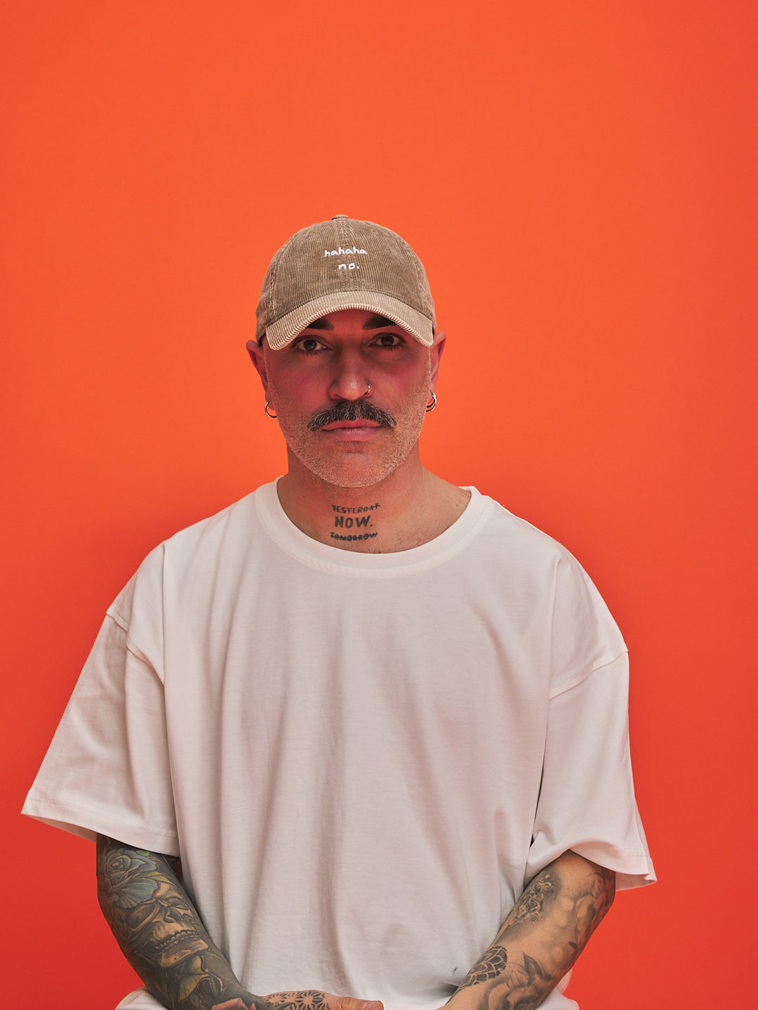 Person wearing a beige cap and white t-shirt against an orange background
