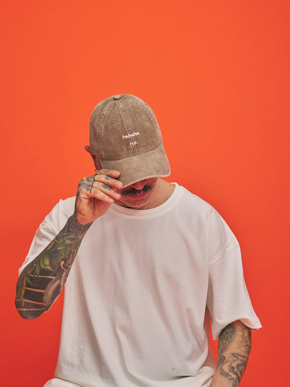 Person wearing a beige cap and white t-shirt against an orange background