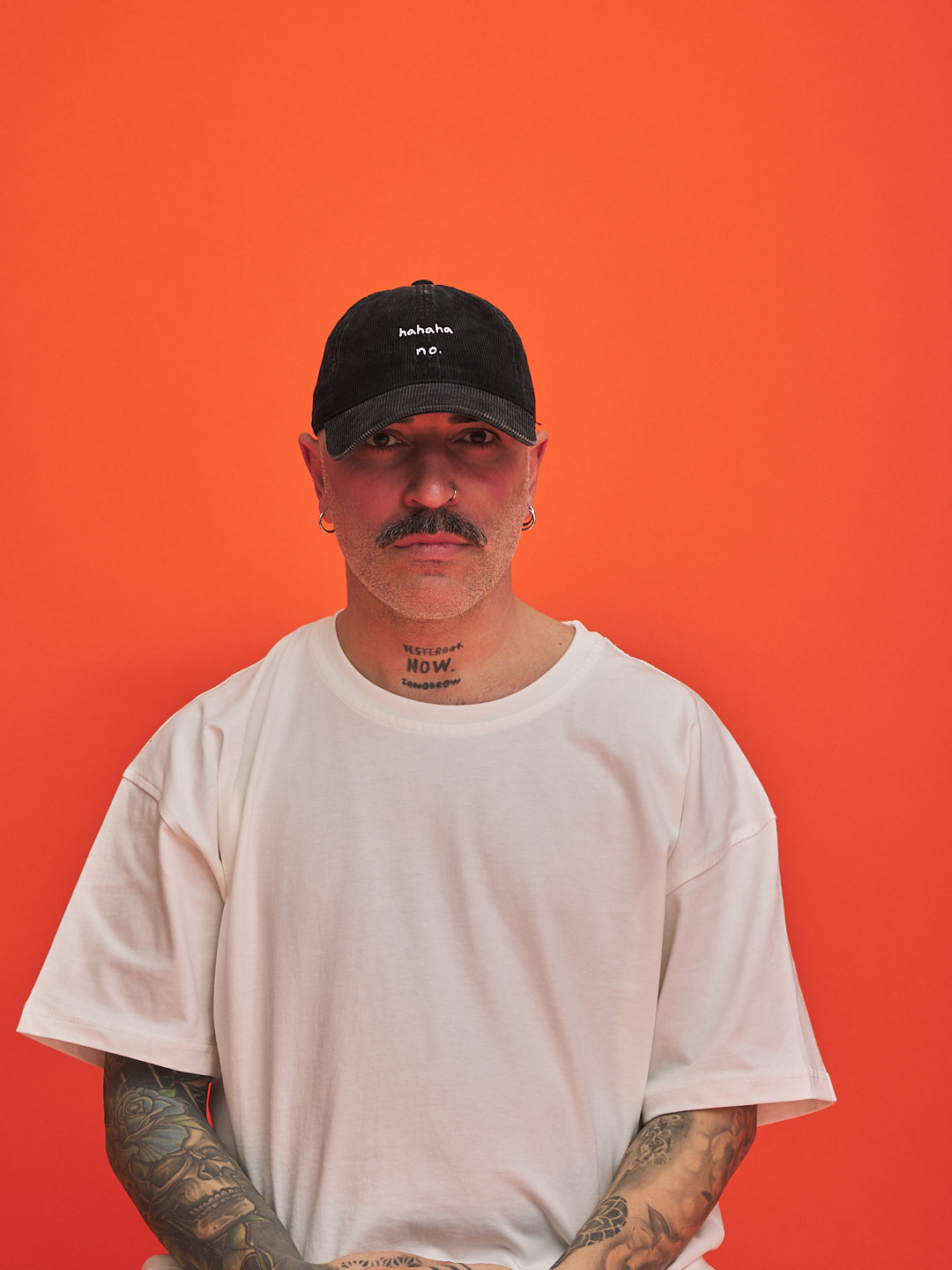 Man wearing a black cap and white t-shirt against an orange background