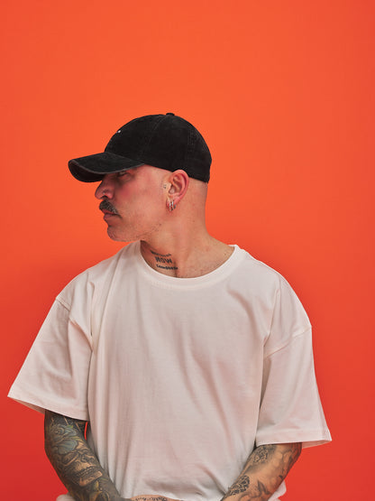 Man wearing a black cap and white t-shirt against an orange background