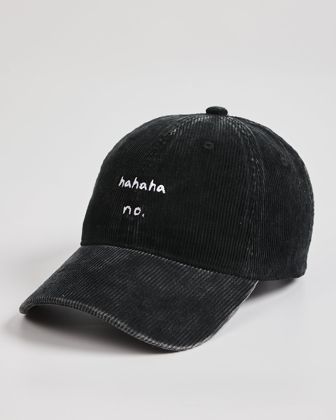 Black corduroy cap with white text on a light gray background