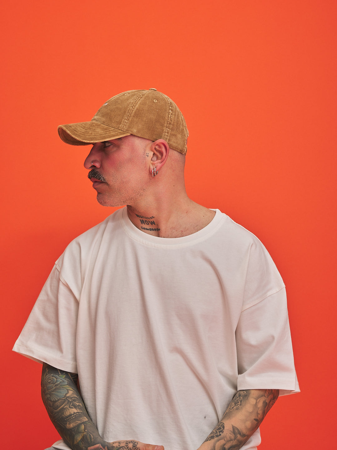 Person wearing Hahaha No Camel Corduroy Cap and white t-shirt against an orange background