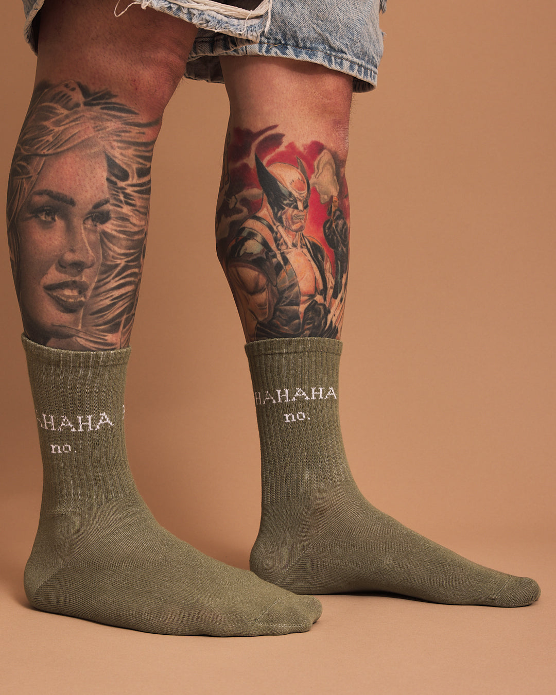 Person wearing green socks with 'HAHA no.' text, standing against a brown background