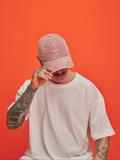 Person wearing a pink cap and white t-shirt against an orange background