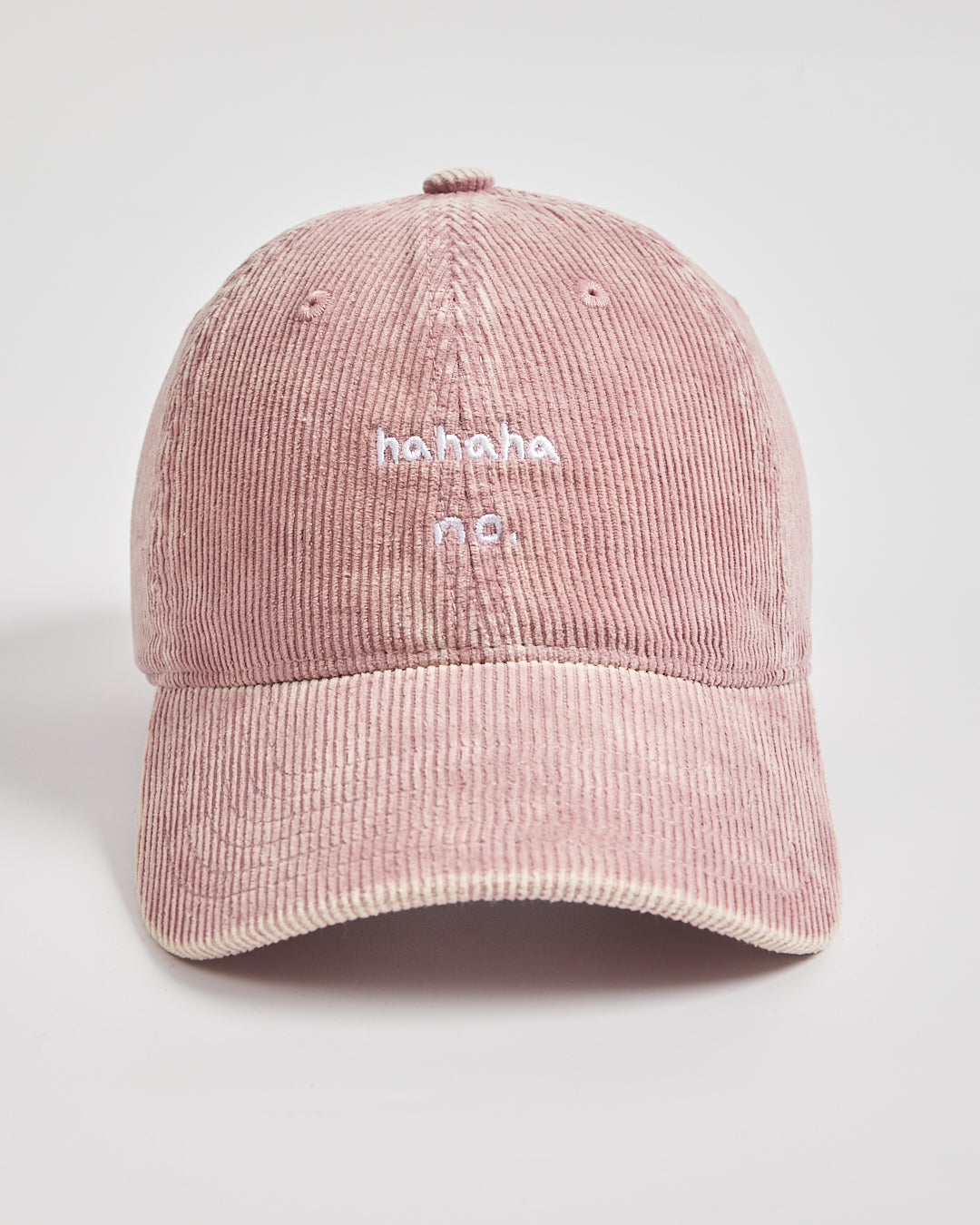 Pink corduroy cap with 'ahaha no.' text on a light gray background