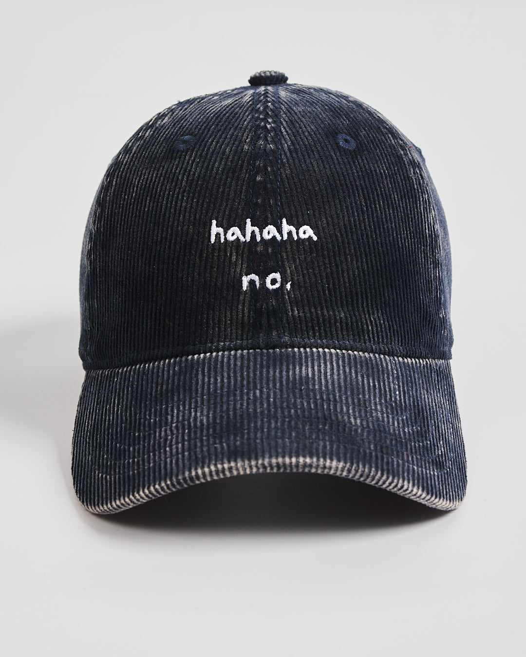 Navy blue corduroy cap with 'hahaha no.' text on a light gray background