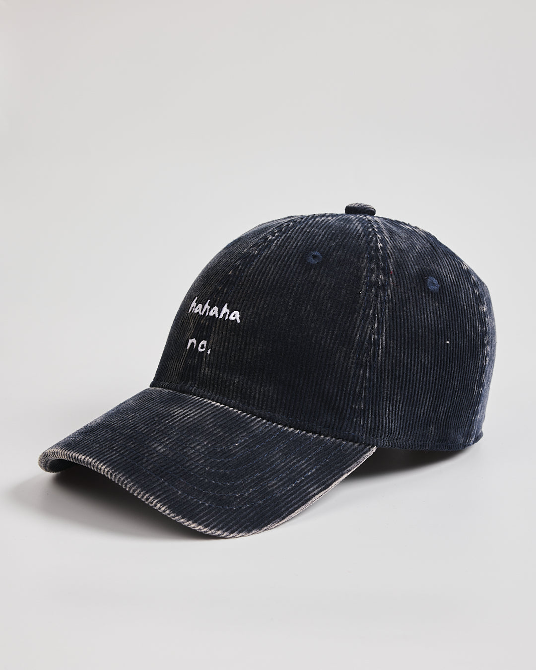 Navy blue corduroy cap with white text on a light gray background
