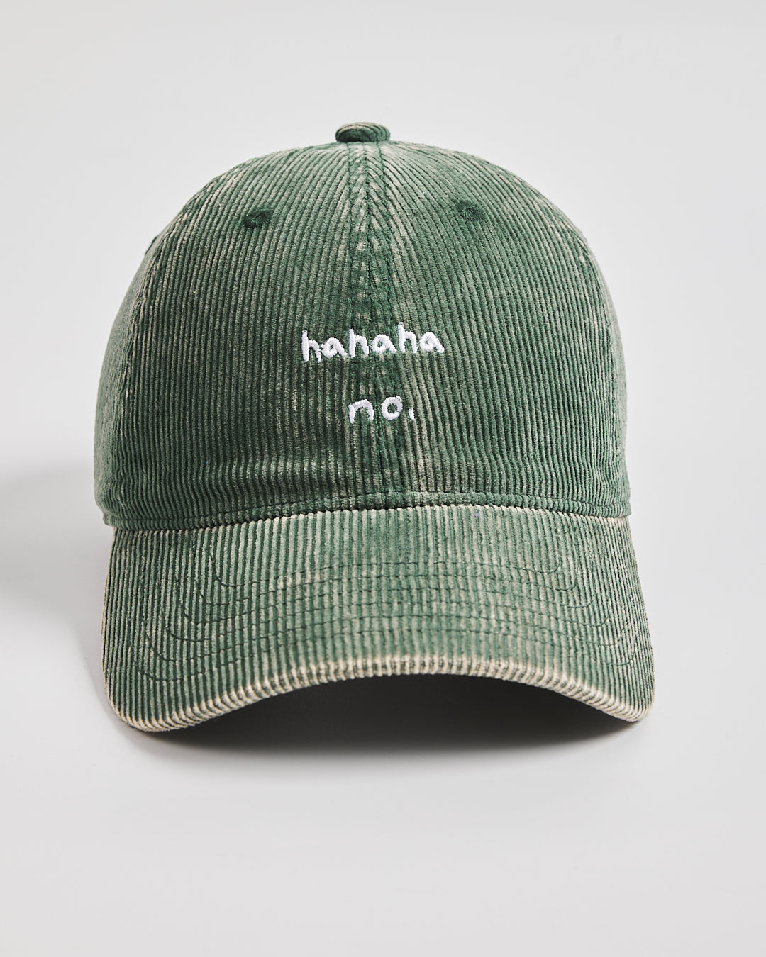Green corduroy cap with 'hahaha no.' text on a light gray background