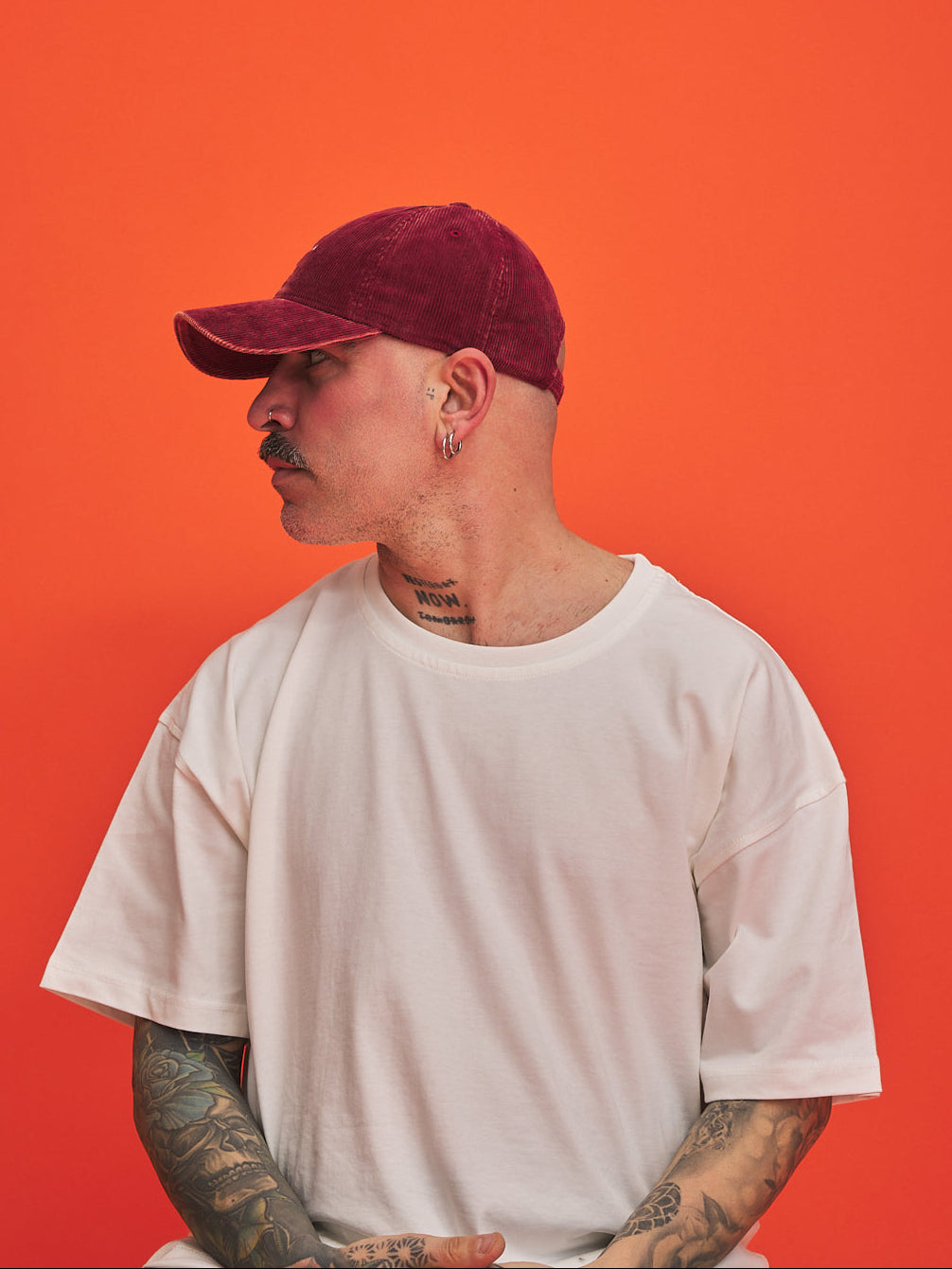 Person wearing Hahaha No Red Corduroy Cap and white t-shirt against an orange background