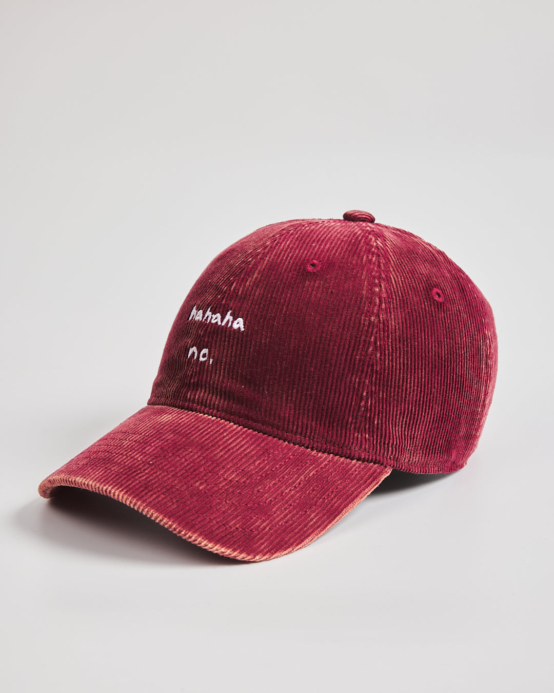 Red corduroy cap with white text on a light gray background