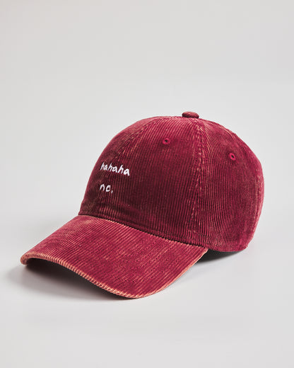 Red corduroy cap with white text on a light gray background