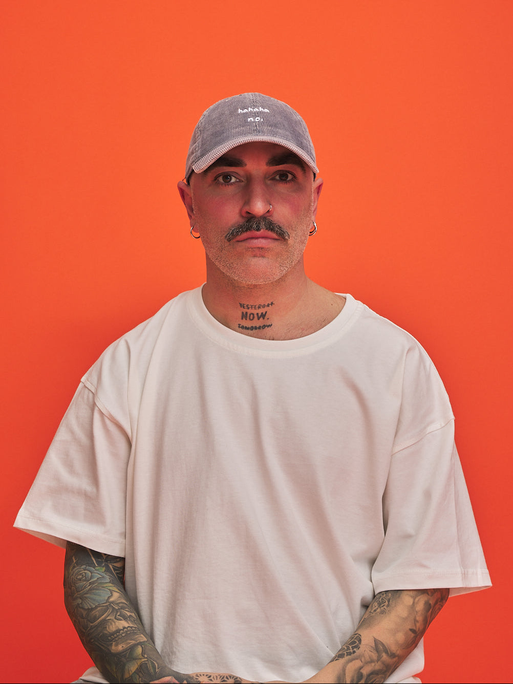 Man wearing a cap and white t-shirt against an orange background