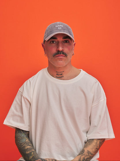 Man wearing a cap and white t-shirt against an orange background
