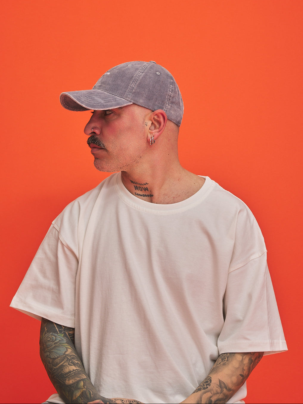Person wearing a gray cap and white t-shirt against an orange background