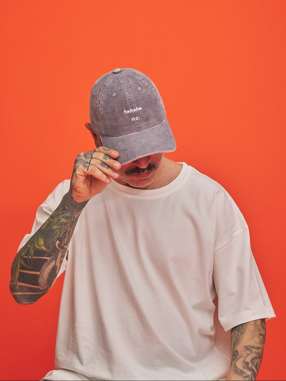 Person wearing a gray cap and white t-shirt against an orange background
