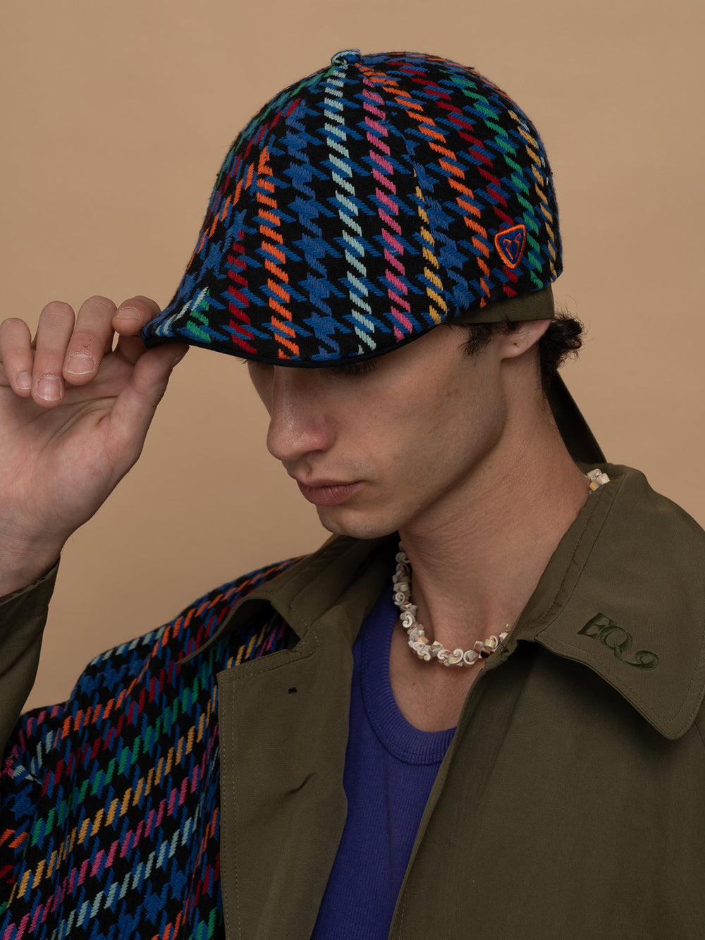 Person wearing Havana Indigo Casket Hat and brown jacket against a beige background