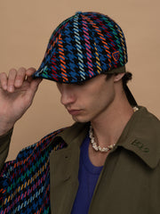 Person wearing Havana Indigo Casket Hat and brown jacket against a beige background