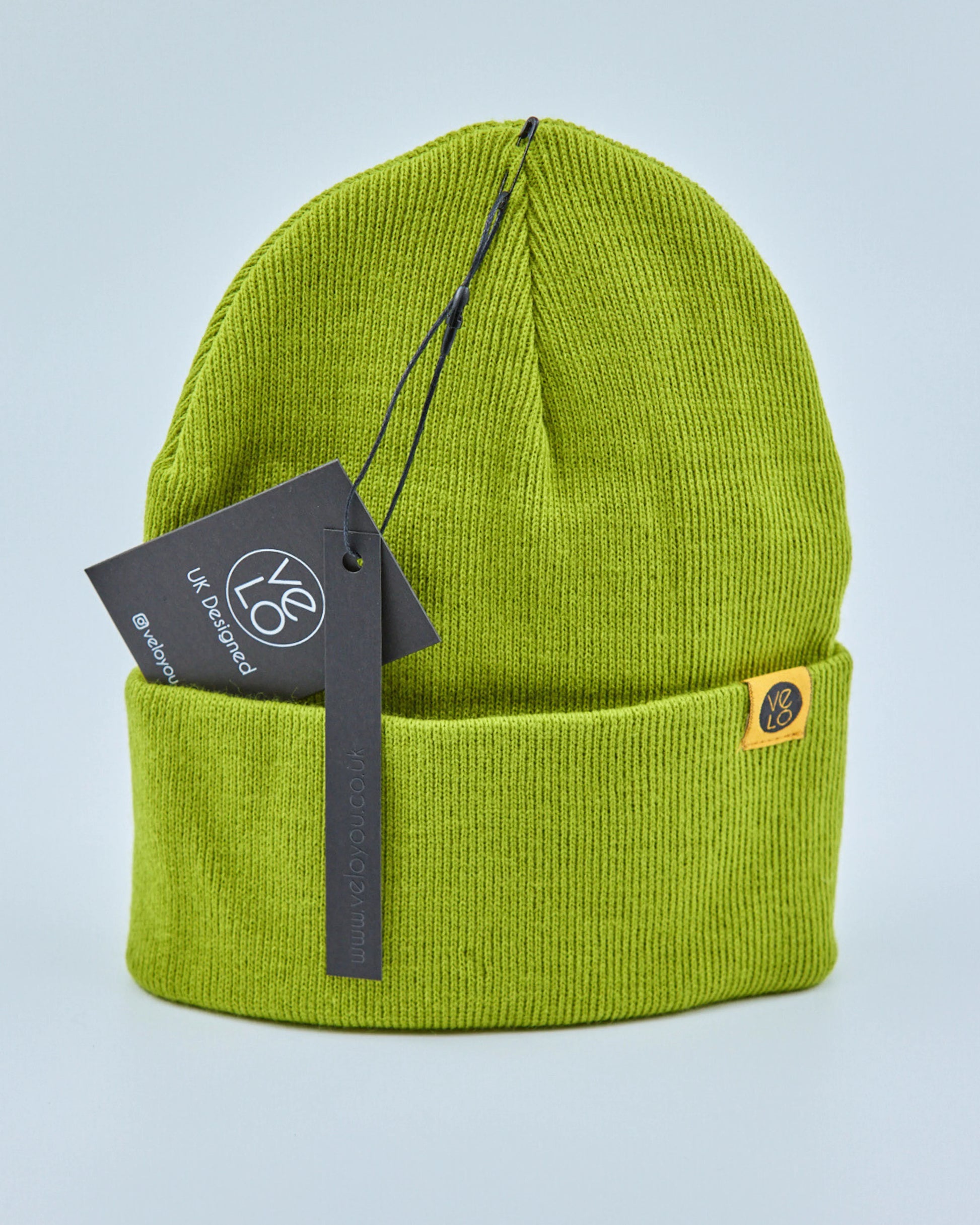 Lime green beanie with a tag on a light blue background